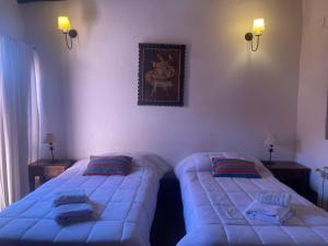 1 dormitorio con 2 camas individuales y una foto en la pared en Posada Con Los Ángeles en Tilcara