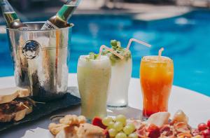 3 boissons sur une table à côté d'une piscine dans l'établissement Posada Suiza by Prima Collection, à San Miguel del Monte