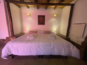 a bedroom with a large bed with two towels on it at Posada Con Los Ángeles in Tilcara