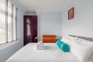 a bedroom with a white bed with blue pillows at Tasteful & Homely 1BD Flat - Brixton in London