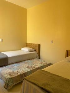 two beds in a room with yellow walls at Pousada Vila das Lagoas in Santo Amaro +99 photos