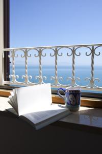 an open book and a coffee cup on a table with a window at La Lanterna in Cetara