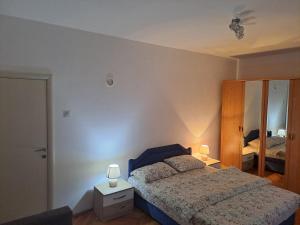 a bedroom with a bed with two lamps and a mirror at Apartman Crno Jezero in Žabljak