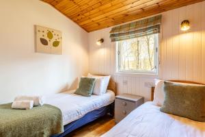 two beds in a small room with a window at Heather Lodge 1 with Hot Tub in Belladrum
