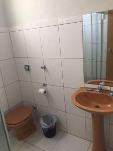 La salle de bains est pourvue de toilettes, d'un lavabo et d'un miroir. dans l'établissement ORSI HOTEL, à Araguari
