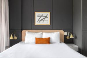 um quarto com uma cama branca e uma almofada laranja em Tabas - Condomínio Forma Itaim em São Paulo