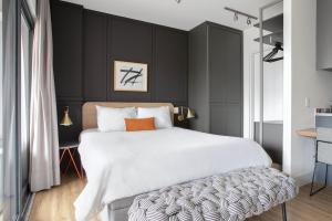 um quarto com uma grande cama branca e uma parede preta em Tabas - Condomínio Forma Itaim em São Paulo