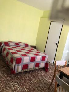 1 cama roja y blanca en una habitación con mesa en Monoambiente en km3 en Comodoro Rivadavia