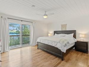 Un dormitorio blanco con una cama y una ventana grande. en Getaway Cottage LAKE FRONT Muskoka Room Kayaks, en Dwight