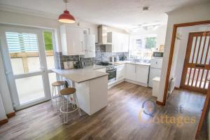 a kitchen with white cabinets and a wooden floor at Quayside - Rye in Rye