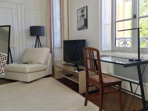 a living room with a chair a desk and a television at Grand appartement exceptionnel Centre-ville in Dieulefit