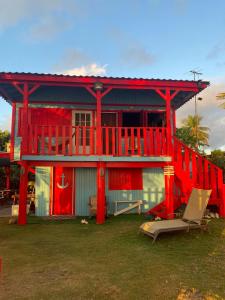 Maison rouge avec balcon et terrasse dans l'établissement Sunrise Cottage, à Fajardo