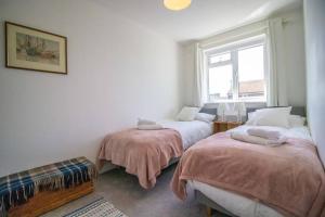 2 camas en una habitación con ventana en Rosemary Cottage Camber Sands - 1 min to beach en Camber