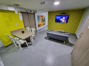 ein Wohnzimmer mit einem Tisch, einem Sofa und einem TV in der Unterkunft Tranquilo Apartamento Central Cerca a la Playa Puerto Colombia in Puerto Colombia