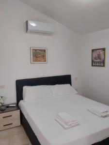 1 dormitorio con cama blanca y mesita de noche en Appartamento Indipendente, en Canino