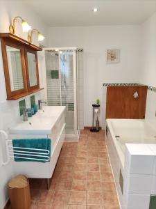 uma casa de banho com 2 lavatórios, uma banheira e um chuveiro em Villas du Lac em Clairvaux-les-Lacs