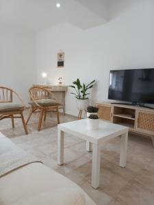 a living room with a white table and a tv at Helena's House in Nazaré