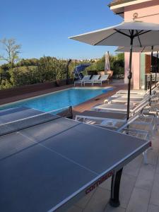 una mesa de ping pong y una sombrilla junto a la piscina en Sentirsi a casa, en Portacomaro