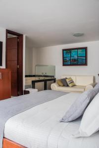 um quarto com uma cama grande e um sofá em Nogal Suite Hotel em Pasto
