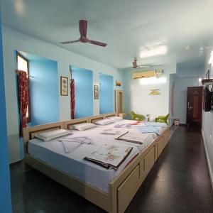1 dormitorio con 4 camas en una habitación con paredes azules en Mango Tree Homestay en Hampi