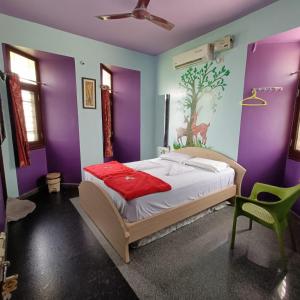 a bedroom with purple and green walls and a bed at Mango Tree Homestay in Hampi +53 photos