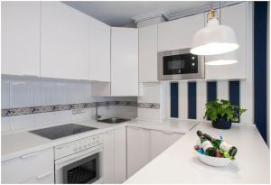 a kitchen with white cabinets and a bowl of wine bottles on a counter at Luminoso y Azul VUT 4654 AS in Avilés