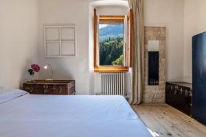 1 dormitorio con cama blanca y ventana en Casa nel Borgo Iris, en Breguzzo