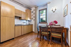 una cocina con armarios de madera y una mesa con sillas. en Casa nel Borgo Iris, en Breguzzo