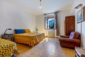 a bedroom with a bed and a couch and a chair at Casa nel Borgo Iris in Breguzzo