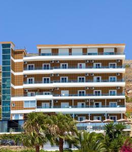 a tall building with palm trees in front of it at Mucobega Hotel 2 in Sarandë