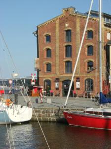 
a small boat docked in a harbor next to a large building at Hotel Alter Hafenspeicher in Stralsund
