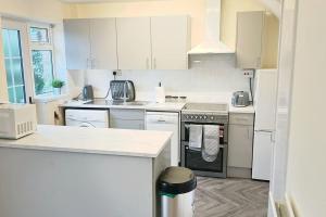 a kitchen with white cabinets and a stove top oven at Lovely 3 Bed with Free parking-Families, Professionals and Contractors Welcome in Luton