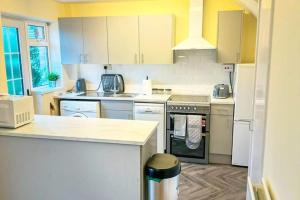 a kitchen with white cabinets and a stove top oven at Lovely 3 Bed with Free parking-Families, Professionals and Contractors Welcome in Luton