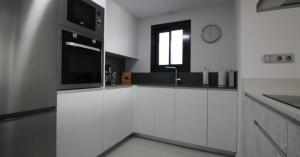 een keuken met witte kasten en een klok aan de muur bij Apartment Margarita 2 in Torrevieja