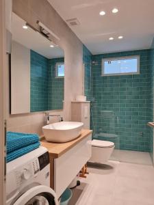 a bathroom with a sink and a toilet and green tiles at Beachfront Comfort Apartments SINAJKO in Podgora