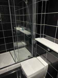 a black tiled bathroom with a toilet and a shower at Twin Room With En-Suite in Edinburgh