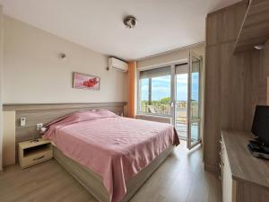 um quarto com uma cama rosa e uma janela em Golf Villa Ariel em Kavarna