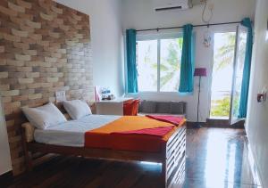 a bedroom with a bed and a brick wall at Nenapu Beachfront Mangalore in Mangalore