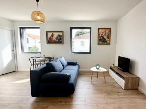 sala de estar con sofá azul y TV en LES ARÈNES - Lumineux - Centre-Ville en Mont-de-Marsan