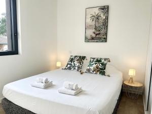 Un dormitorio con una cama blanca con toallas. en LES ARÈNES - Lumineux - Centre-Ville en Mont-de-Marsan