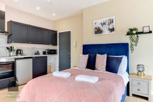 a bedroom with a large bed with a blue headboard at Bright studio with turret and parking by Eagle Owl Property in Worthing