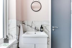 a white bathroom with a sink and a mirror at Bright studio with turret and parking by Eagle Owl Property in Worthing