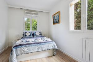 ein Schlafzimmer mit einem Bett und zwei Fenstern in der Unterkunft Maison charmante avec jardin et parking offert Paris St Cloud in Saint-Cloud