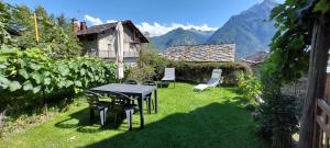 a table and chairs in a yard with mountains at Le Chaton Fait Ronron in Quart