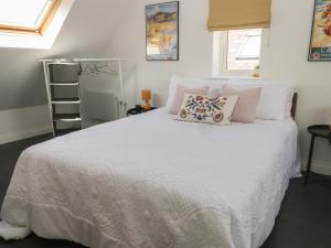 um quarto com uma grande cama branca com almofadas em Bodlywydd Fawr - Annexe em Ruthin