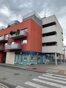 a red building with balconies on a street at Apartments Spačilova nearly center in Komárov