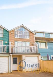 a large house with a deck and two garage doors at Sandunes House in Camber