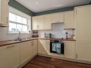 uma cozinha com armários brancos, um lavatório e uma janela em Cherry Tree House em Highbridge