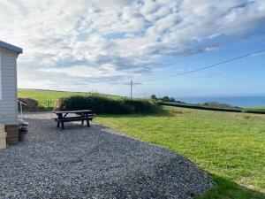 a bench sitting on the gravel near a field at Mwnt Sea View Caravan with Free WiFi in Cardigan