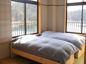 un letto in una stanza con due grandi finestre di kazeto a Ōda